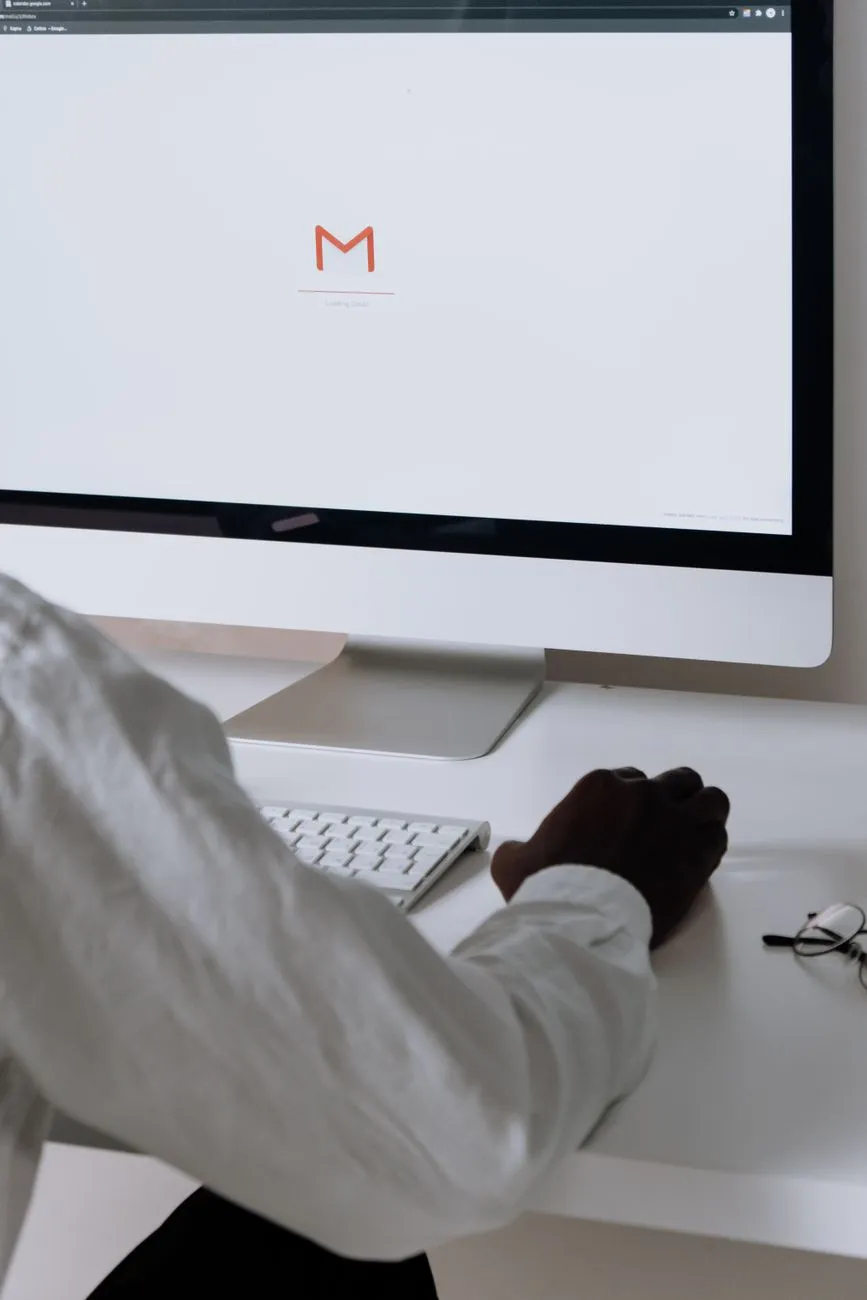 A businessman at a desk checking his email inbox on a desktop monitor