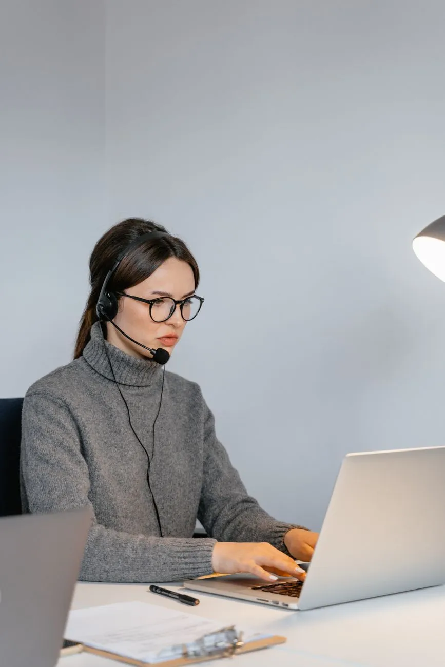 A customer support agent wearing a headset, reviewing an escalated chat conversation on a laptop