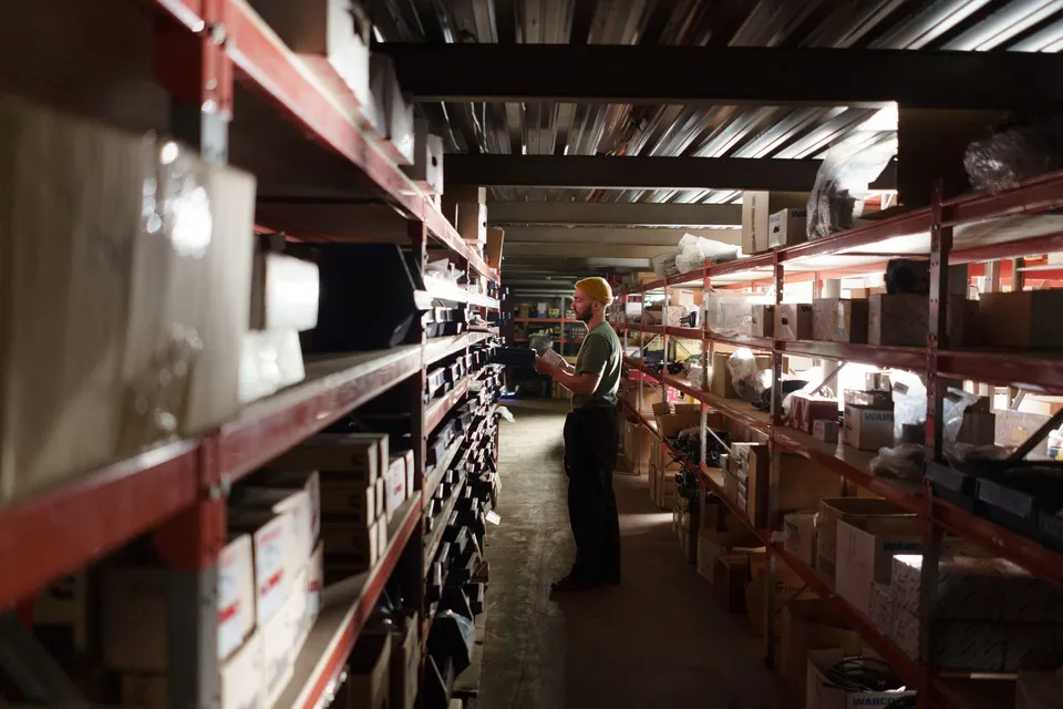 A worker checking inventory on warehouse shelving during a store migration