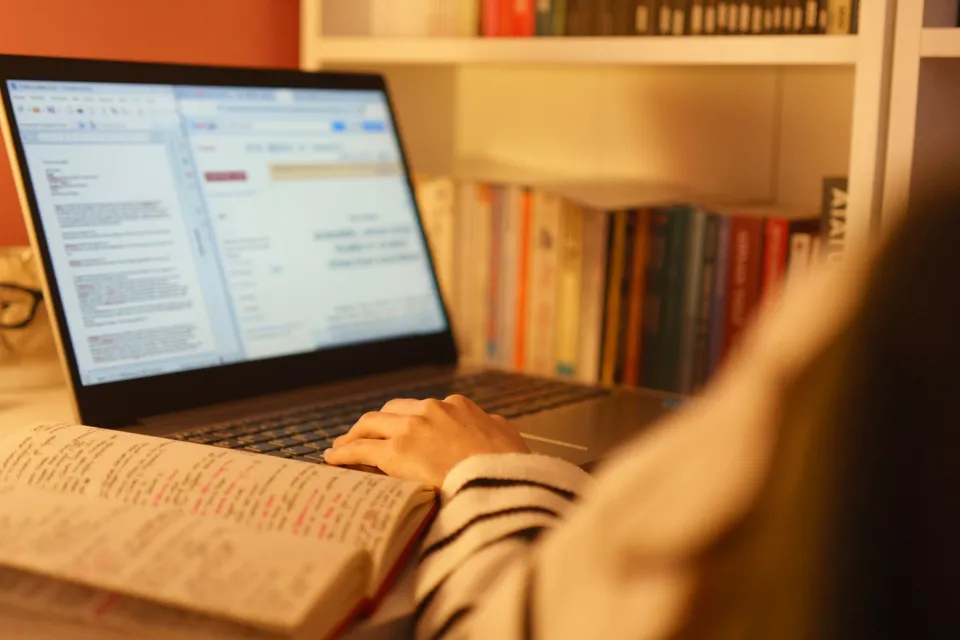Person researching SEO, AEO, and GEO on a laptop with handwritten notes