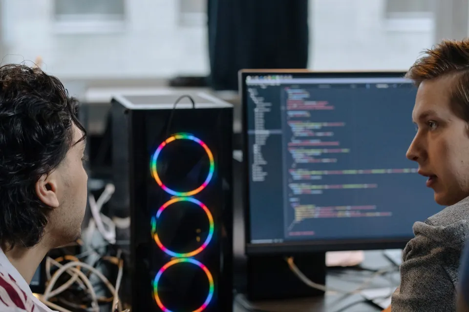 Two engineers reviewing code together on a monitor during a technical consulting session